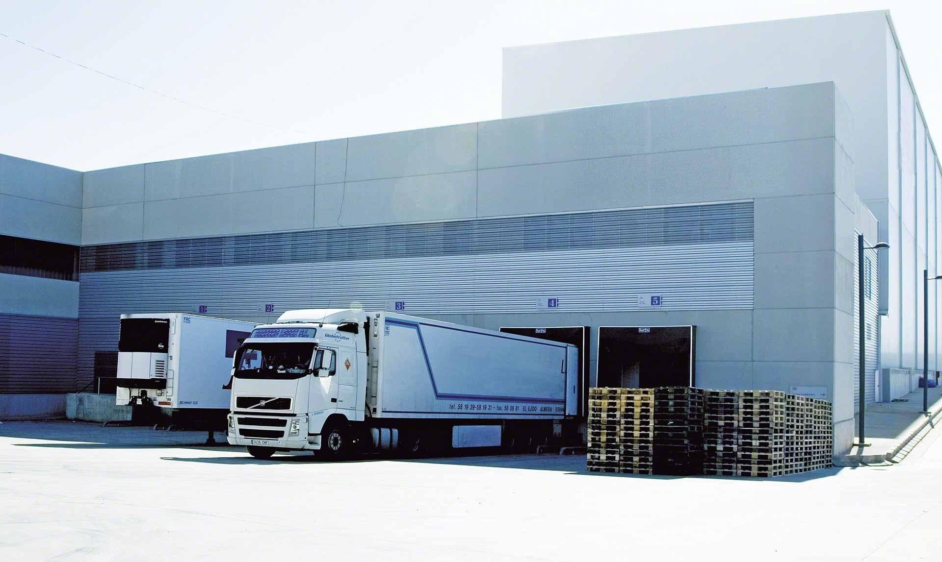 Camiones de mercaderías descargan en el almacén como parte de las operaciones de cross-docking Camiones de mercaderías descargan en el almacén como parte de las operaciones de cross-docking