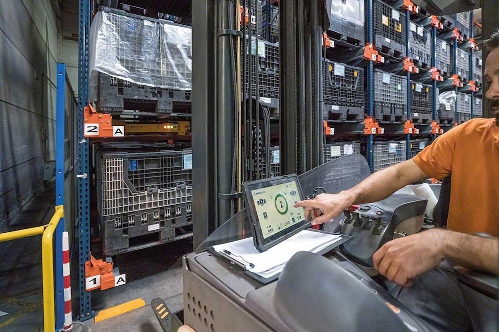 Un operario maneja el Pallet Shuttle desde el montacargas con una tableta digital Un operario maneja el Pallet Shuttle desde el montacargas con una tableta digital